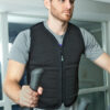 Man working out on elliptical machine while wearing black weighted unisex vest from Power WearHouse