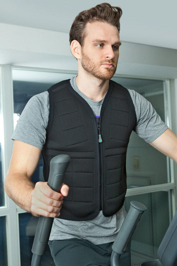 Man working out on elliptical machine while wearing black weighted unisex vest from Power WearHouse