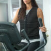 Woman using elliptical workout machine in black weighted unisex vest from Power Wearhouse