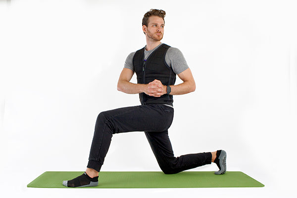A man doing yoga in black yoga studio socks and Power WearHouse weighted vest on green mat