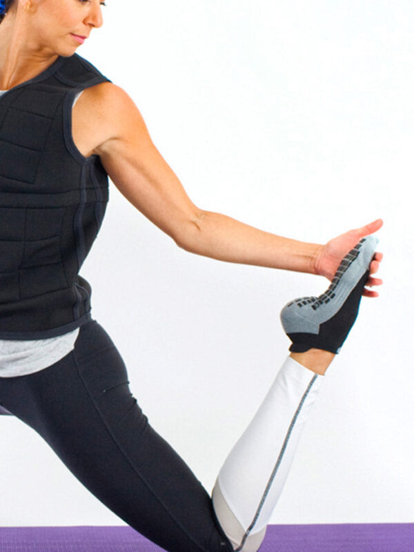 Woman doing yoga in studio grip socks and a Power WearHouse weighted vest
