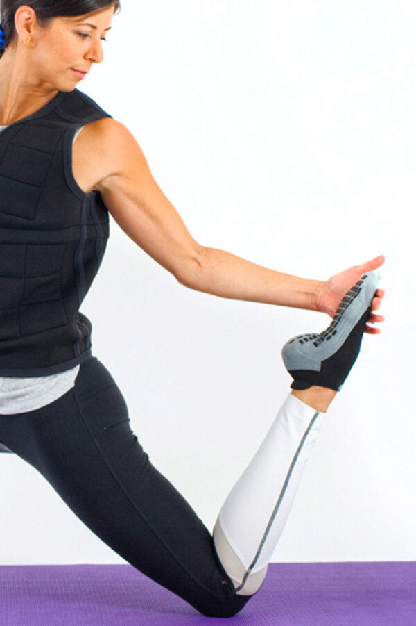 Woman doing yoga in studio grip socks and a Power WearHouse weighted vest